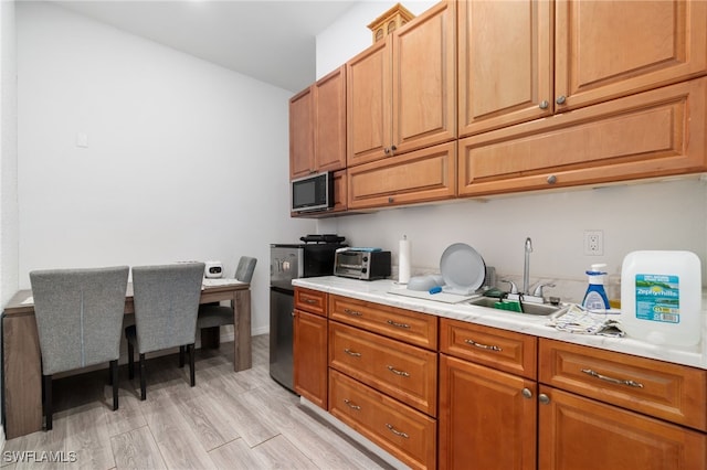 kitchen with sink, built in microwave, and light hardwood / wood-style flooring