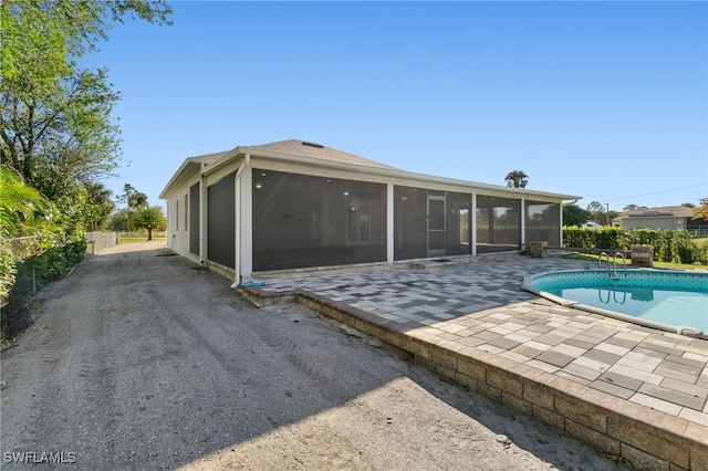 back of property featuring a patio, a fenced in pool, and a sunroom