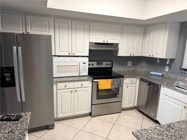 kitchen with white cabinets, light tile patterned flooring, appliances with stainless steel finishes, and dark stone counters