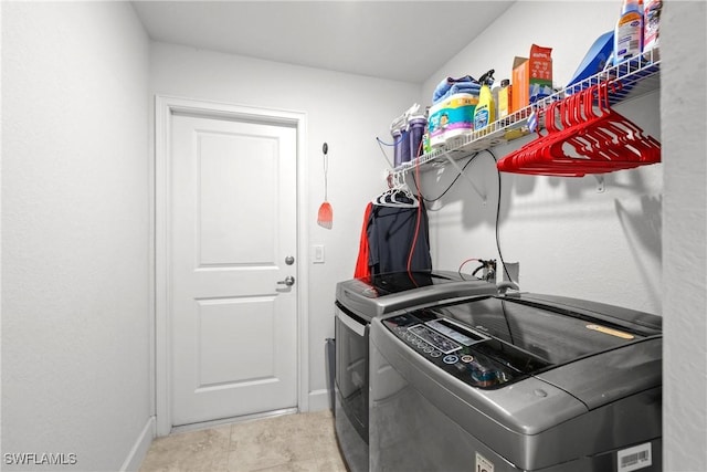 laundry area with light tile patterned floors and washing machine and clothes dryer