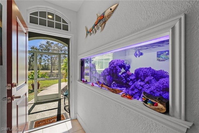 foyer with tile patterned flooring, a textured ceiling, and a wealth of natural light