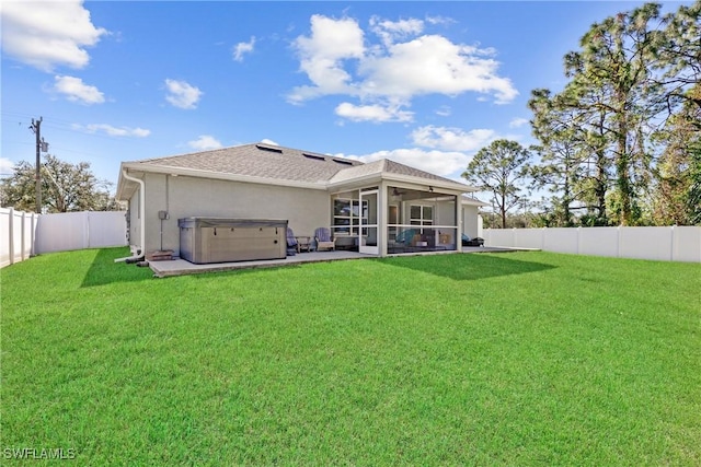 rear view of house featuring a patio area, a sunroom, a yard, and a hot tub