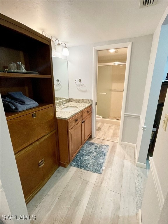 bathroom with hardwood / wood-style flooring, vanity, toilet, and a shower with shower door