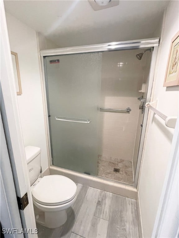 bathroom featuring hardwood / wood-style flooring, toilet, and an enclosed shower