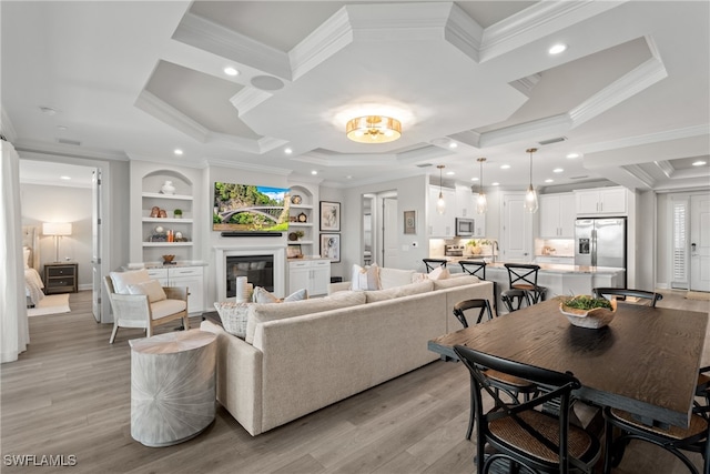 living room featuring a raised ceiling, crown molding, light hardwood / wood-style flooring, and built in features