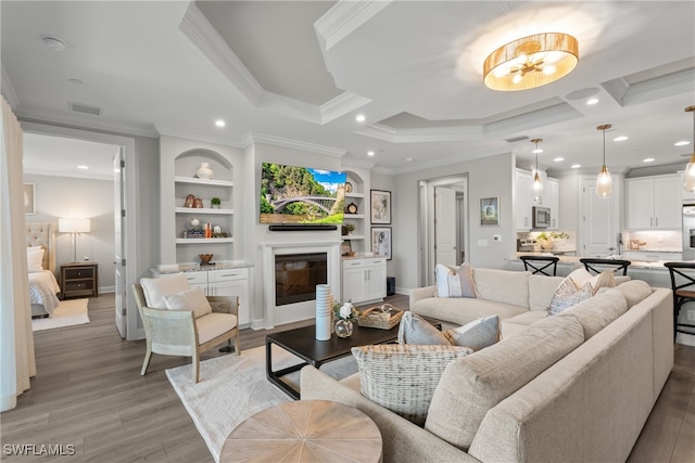 living room with a chandelier, wood-type flooring, built in shelves, and crown molding