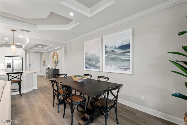 dining space featuring a raised ceiling, crown molding, and light hardwood / wood-style flooring