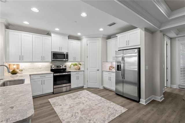 kitchen featuring appliances with stainless steel finishes, crown molding, sink, dark hardwood / wood-style floors, and white cabinetry