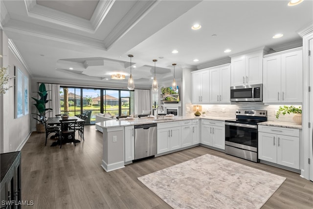 kitchen with white cabinets, light hardwood / wood-style floors, decorative light fixtures, and appliances with stainless steel finishes