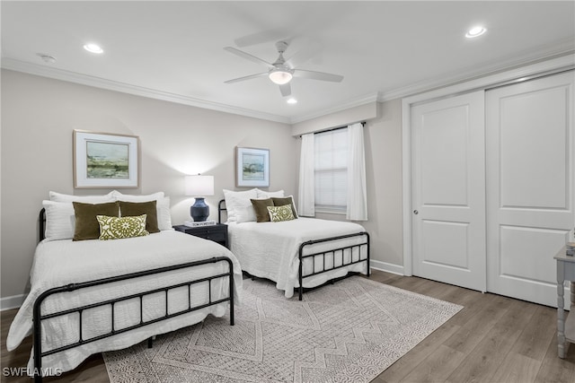 bedroom featuring ceiling fan, light hardwood / wood-style floors, ornamental molding, and a closet