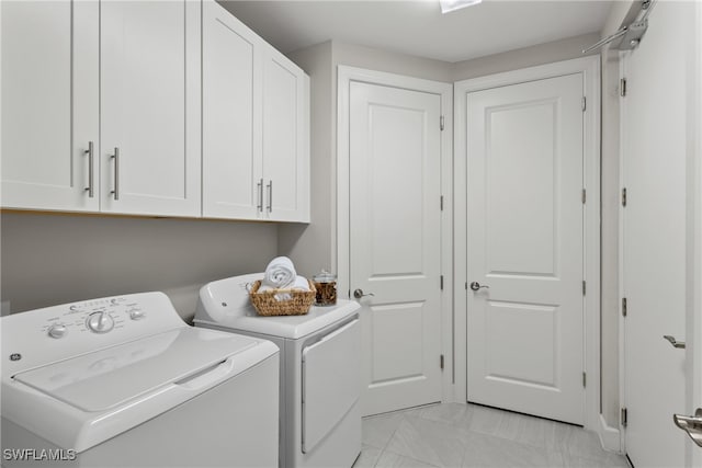 washroom with cabinets and washing machine and clothes dryer