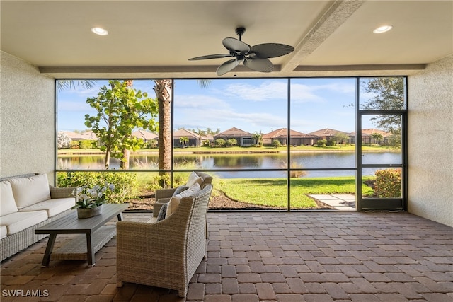 sunroom / solarium featuring a wealth of natural light, ceiling fan, and a water view