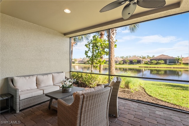 sunroom with ceiling fan and a water view