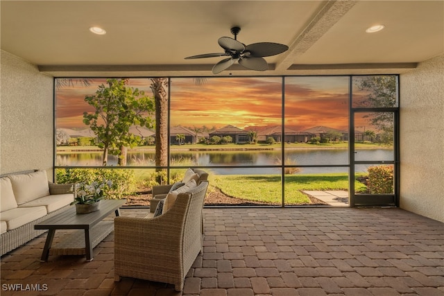 sunroom / solarium with ceiling fan and a water view