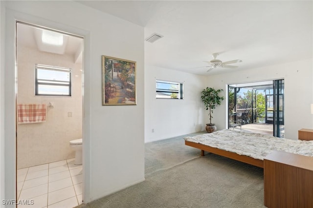 carpeted bedroom with access to outside, multiple windows, ceiling fan, and ensuite bathroom