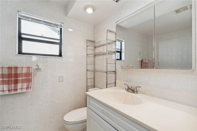 bathroom featuring vanity, toilet, and tile walls