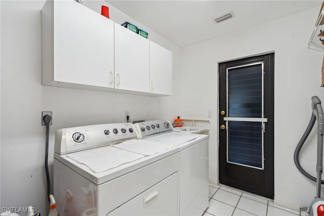 washroom featuring washer and clothes dryer, cabinets, and light tile patterned floors