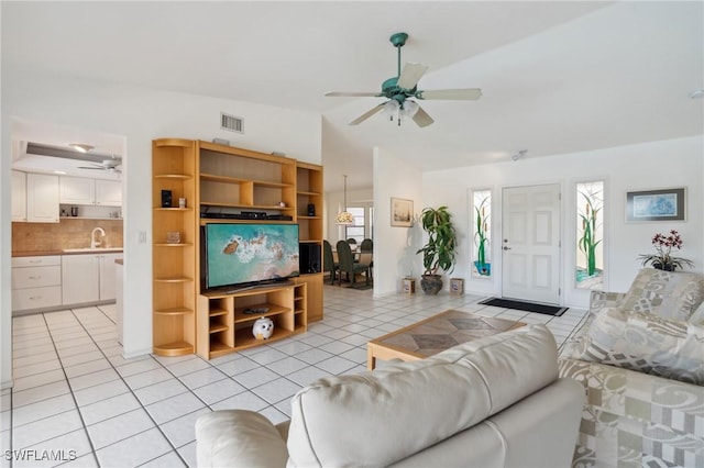 tiled living room with ceiling fan, sink, and lofted ceiling