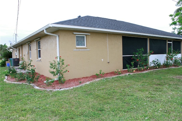 view of side of home with a lawn, a sunroom, and central AC