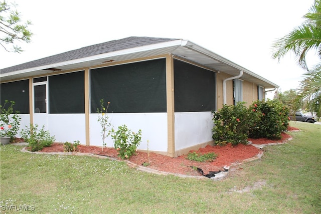 view of side of property with a sunroom and a yard