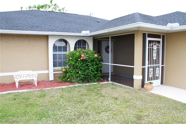 view of exterior entry with a lawn