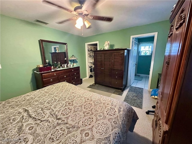 carpeted bedroom with ensuite bathroom and ceiling fan