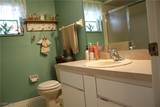 bathroom with a wealth of natural light, vanity, a shower with shower door, and toilet