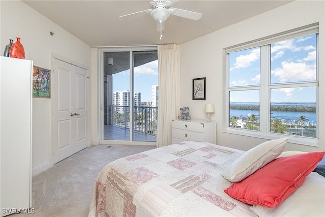 carpeted bedroom featuring a closet, access to outside, ceiling fan, and a water view