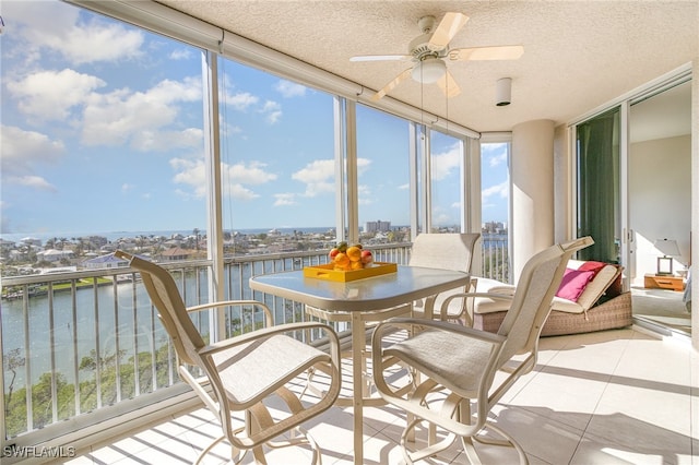 sunroom featuring ceiling fan, plenty of natural light, and a water view