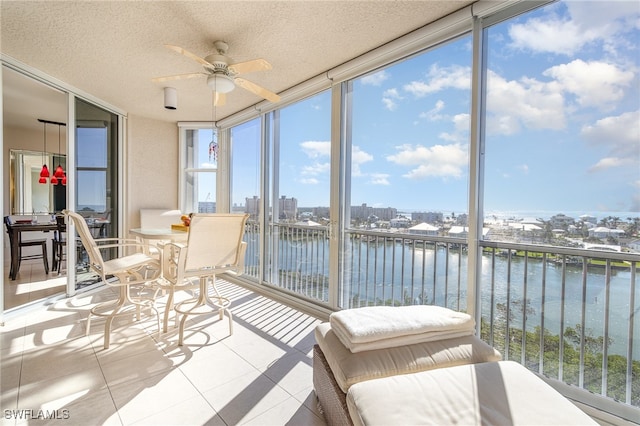 sunroom / solarium with ceiling fan and a water view