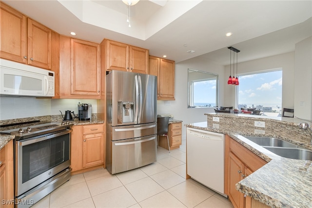 kitchen featuring light stone countertops, appliances with stainless steel finishes, sink, light tile patterned floors, and pendant lighting