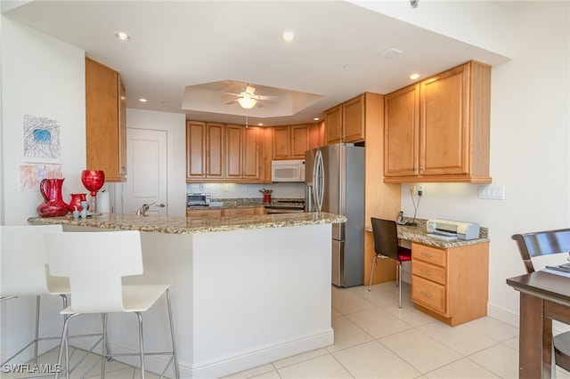 kitchen featuring kitchen peninsula, appliances with stainless steel finishes, light stone countertops, and ceiling fan