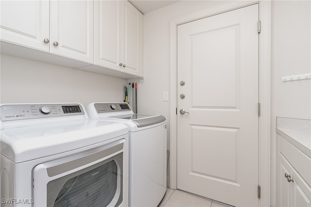 laundry room with washer and clothes dryer, light tile patterned floors, and cabinets