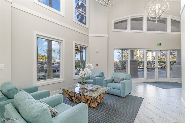 living room featuring a chandelier, french doors, hardwood / wood-style floors, and a high ceiling