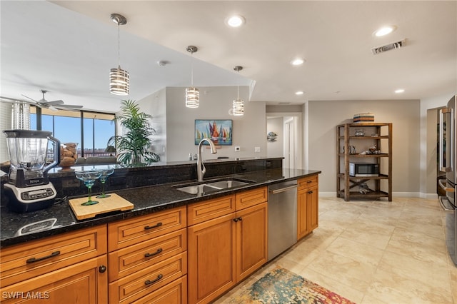 kitchen with dark stone counters, hanging light fixtures, sink, ceiling fan, and appliances with stainless steel finishes