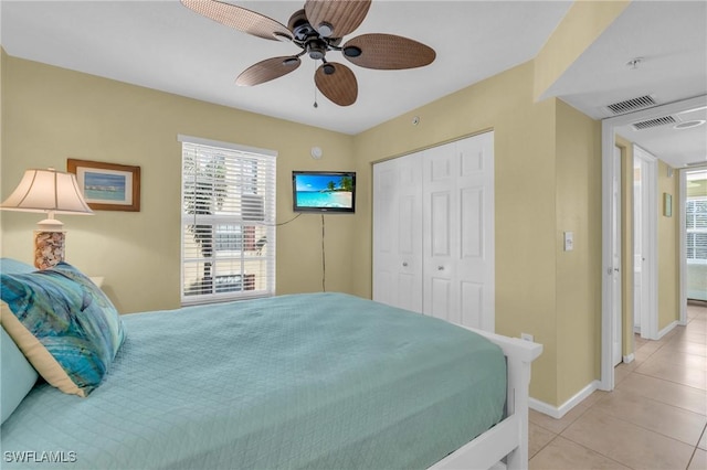 tiled bedroom with ceiling fan and a closet