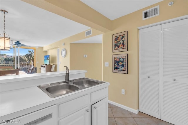 kitchen with sink, light tile patterned floors, dishwasher, white cabinetry, and hanging light fixtures