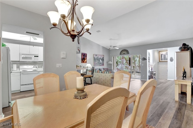 dining space with vaulted ceiling, light hardwood / wood-style floors, and ceiling fan with notable chandelier