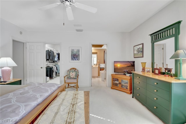 bedroom with ceiling fan, light colored carpet, a closet, and a spacious closet