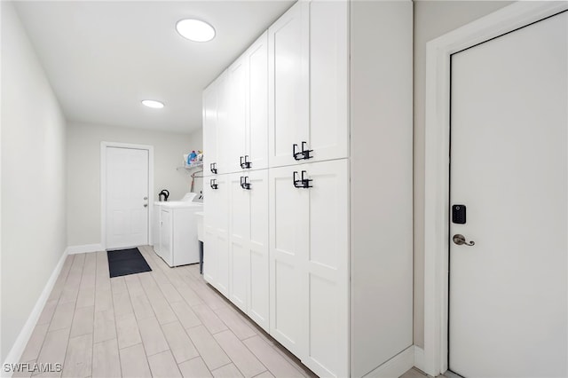 washroom with separate washer and dryer, light hardwood / wood-style flooring, and cabinets