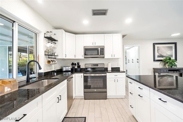 kitchen featuring dark stone countertops, white cabinetry, sink, and appliances with stainless steel finishes