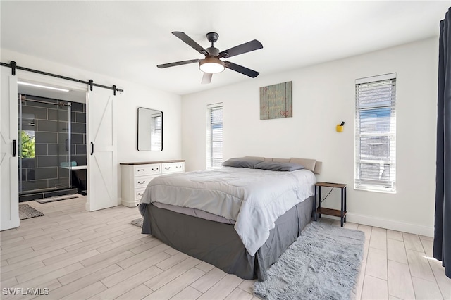 bedroom with ceiling fan, a barn door, light hardwood / wood-style flooring, and multiple windows