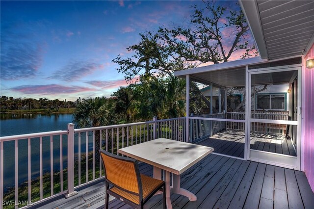 deck at dusk featuring a water view