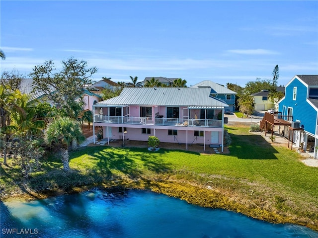 rear view of house featuring a water view, a balcony, and a lawn