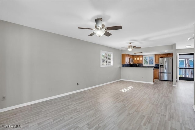 unfurnished living room with light wood-type flooring, plenty of natural light, and ceiling fan