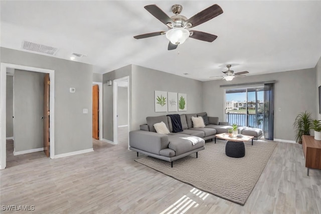 living area featuring baseboards, visible vents, and light wood-style floors