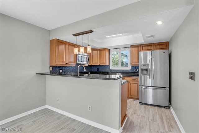 kitchen featuring kitchen peninsula, appliances with stainless steel finishes, backsplash, and a raised ceiling