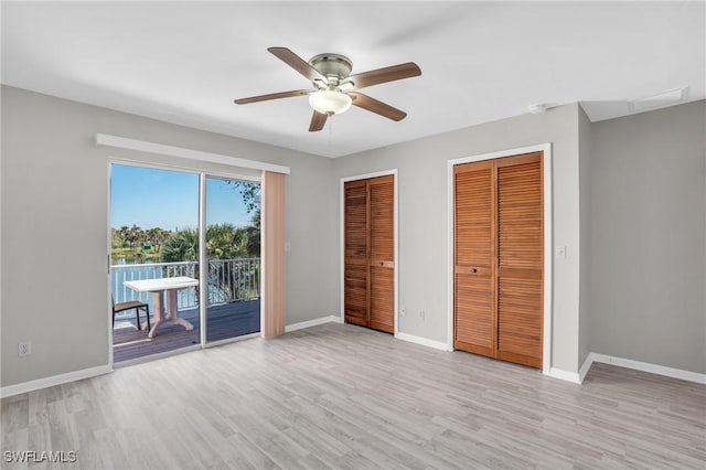 unfurnished bedroom with access to outside, ceiling fan, light hardwood / wood-style flooring, and two closets