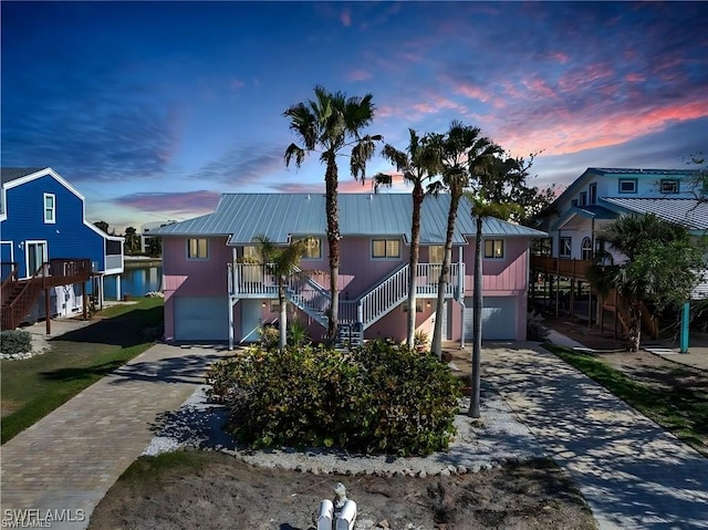 view of front facade featuring decorative driveway, metal roof, and stairs