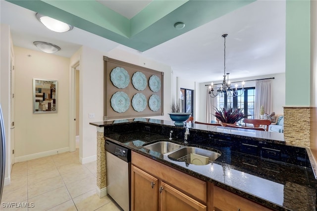 kitchen with stainless steel dishwasher, dark stone counters, sink, decorative light fixtures, and a notable chandelier